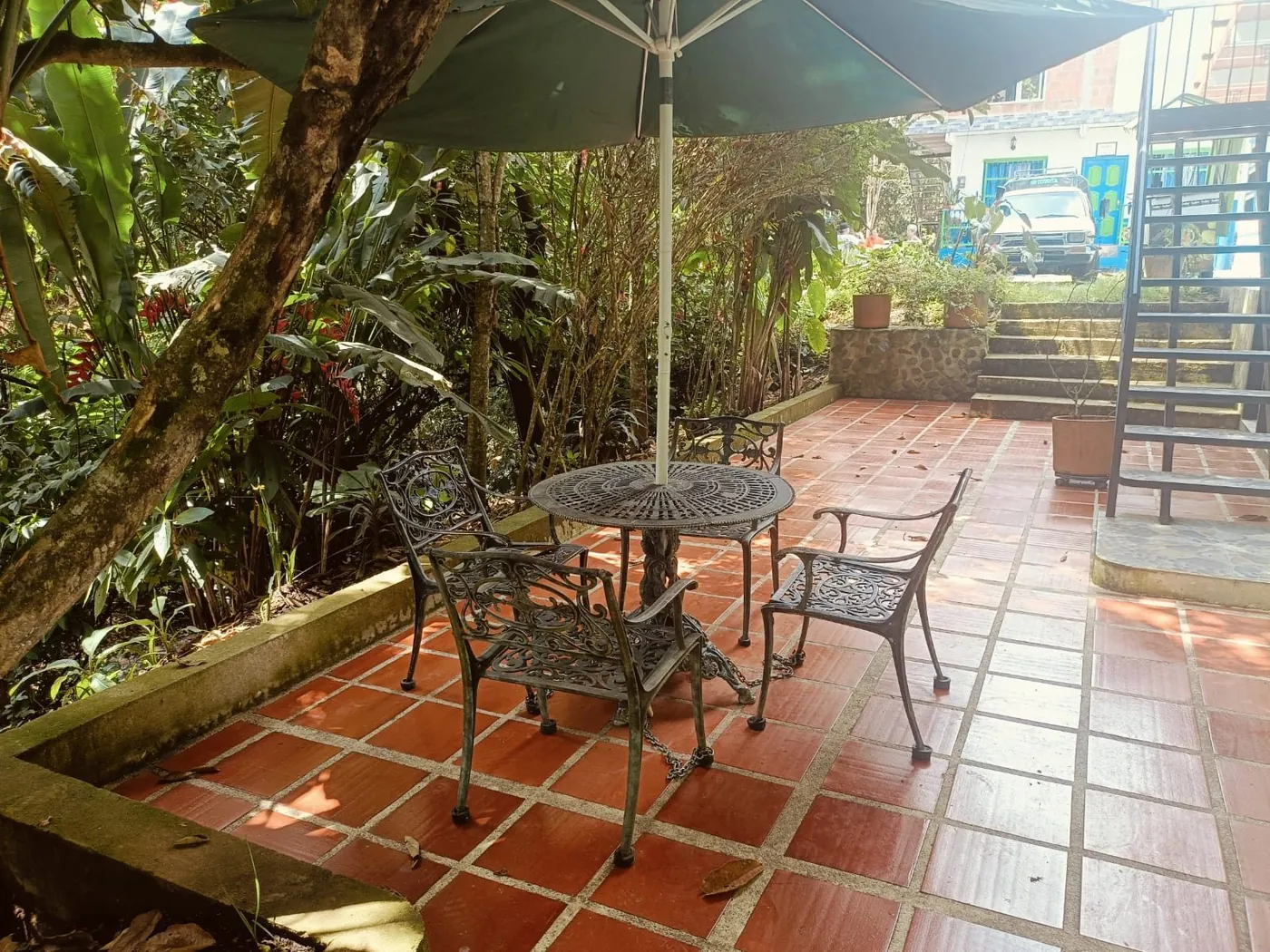 Jardín-terraza con sombrilla entre el verde